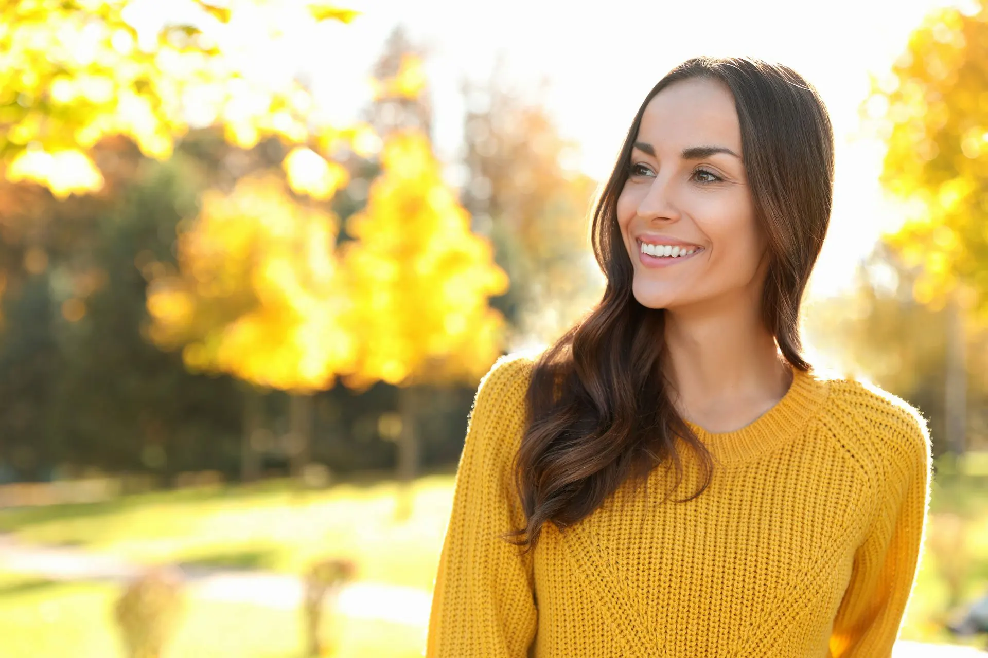 Smiling woman in a yellow sweater outdoors
